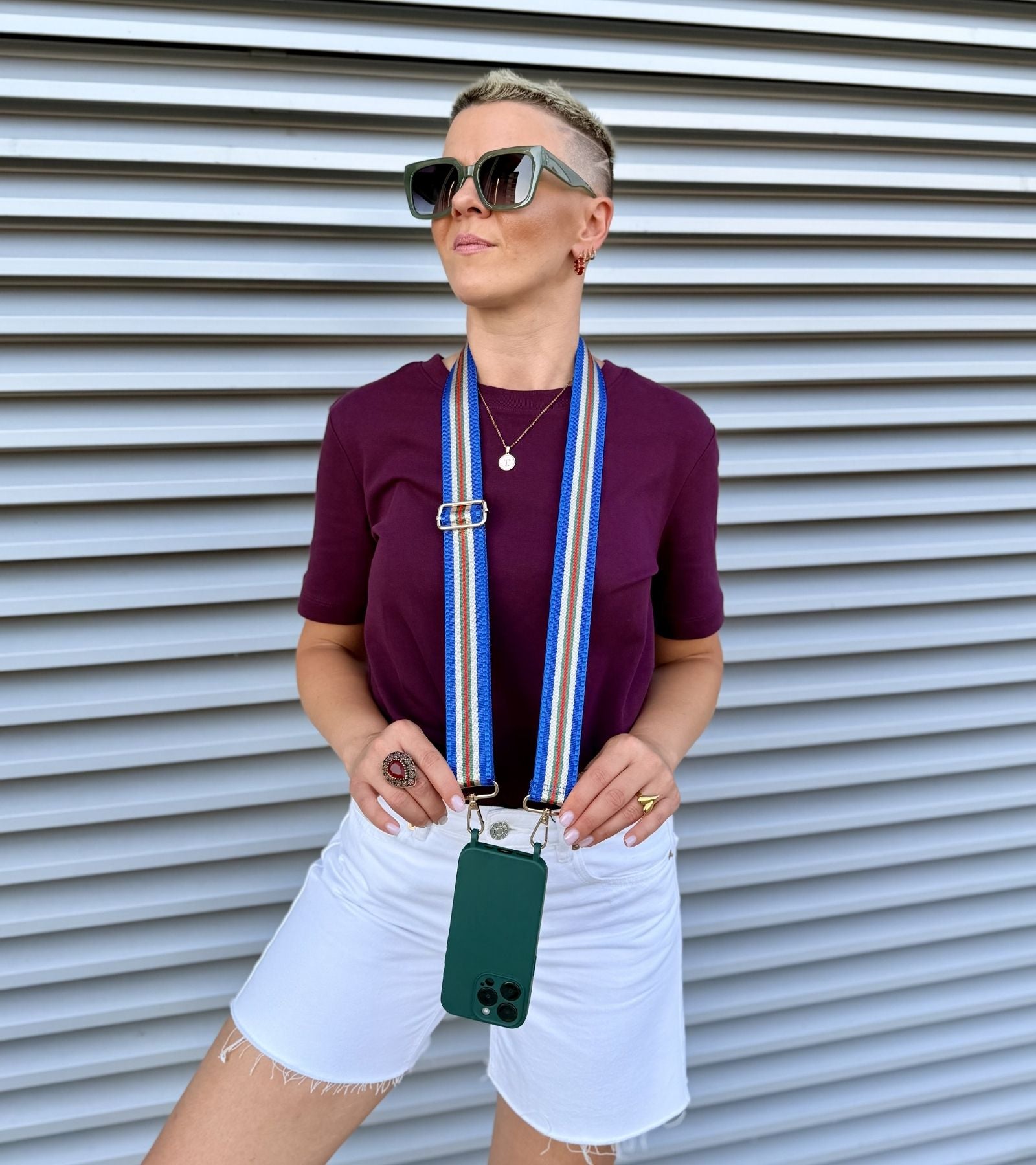 Popruh na mobil v modrej farebnej kombinácii a tmavo zelený kryt na iPhone ako súčasť outfitu - Strappy Set Timeless Monaco Blue na modelke.