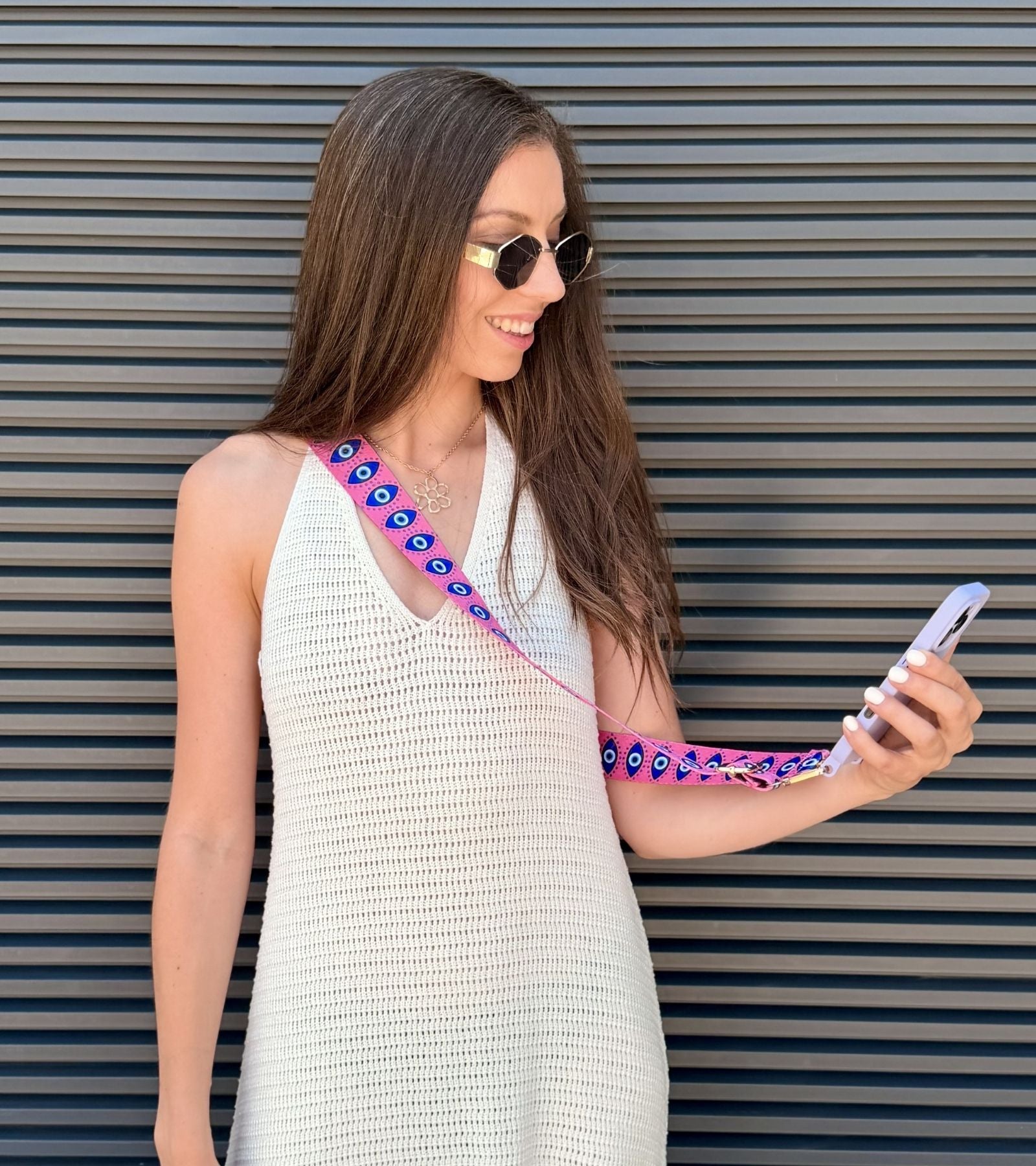 Strappy Set Art Evil Eye na modelke – ružový crossbody popruh na mobil s motívom Evil Eye a fialový kryt na iPhone ako štýlový módny doplnok.