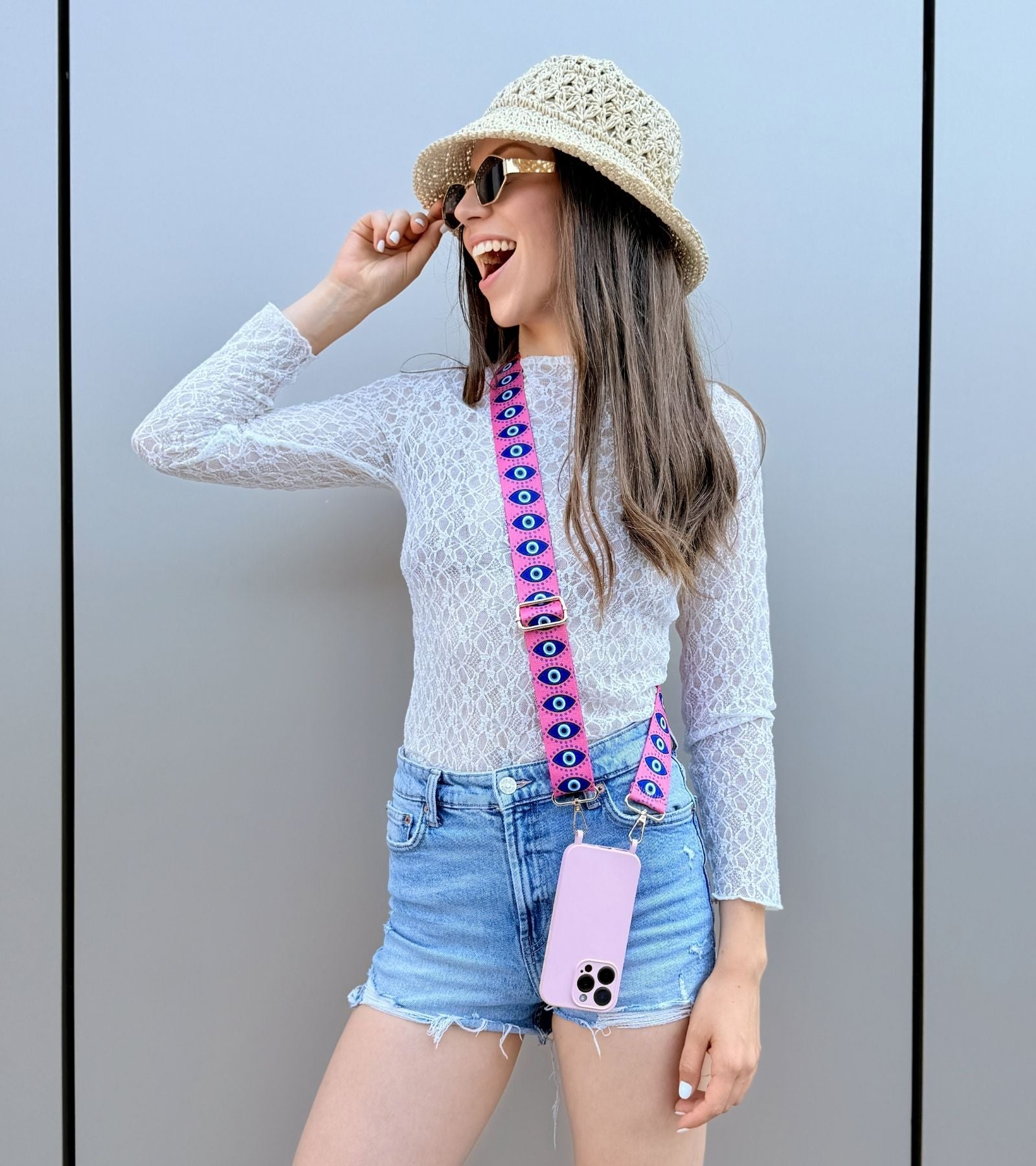 Strappy Set Art Evil Eye na modelke – ružový crossbody popruh na mobil s motívom Evil Eye a fialový kryt na iPhone pre štýlové každodenné nosenie.