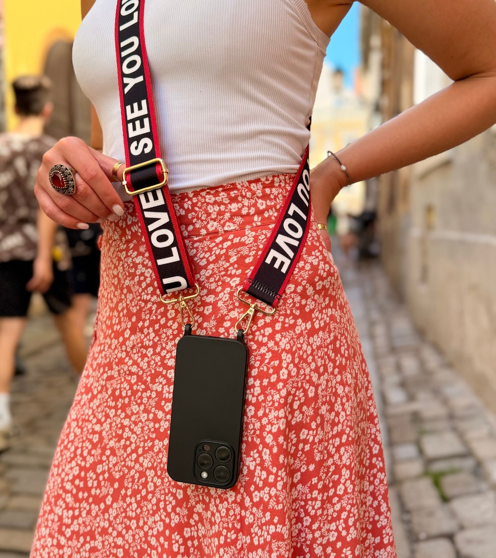 Strappy Set Art Love Statement na modelke – čierny crossbody popruh na mobil Love Statement a čierny kryt na iPhone.