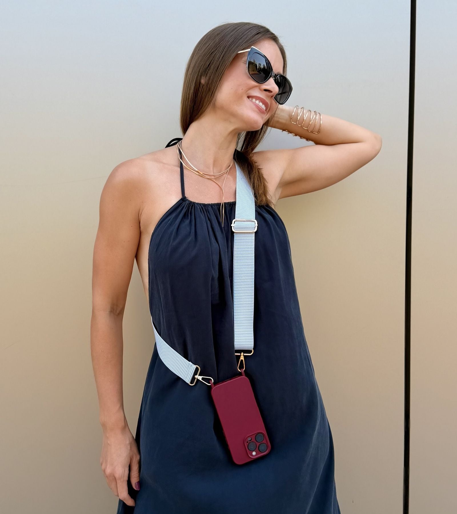 Strappy Set Line Soft Gray na modelke – crossbody popruh na mobil v sivej farebnej kombinácii a bordový kryt na iPhone ako štýlový módny doplnok.
