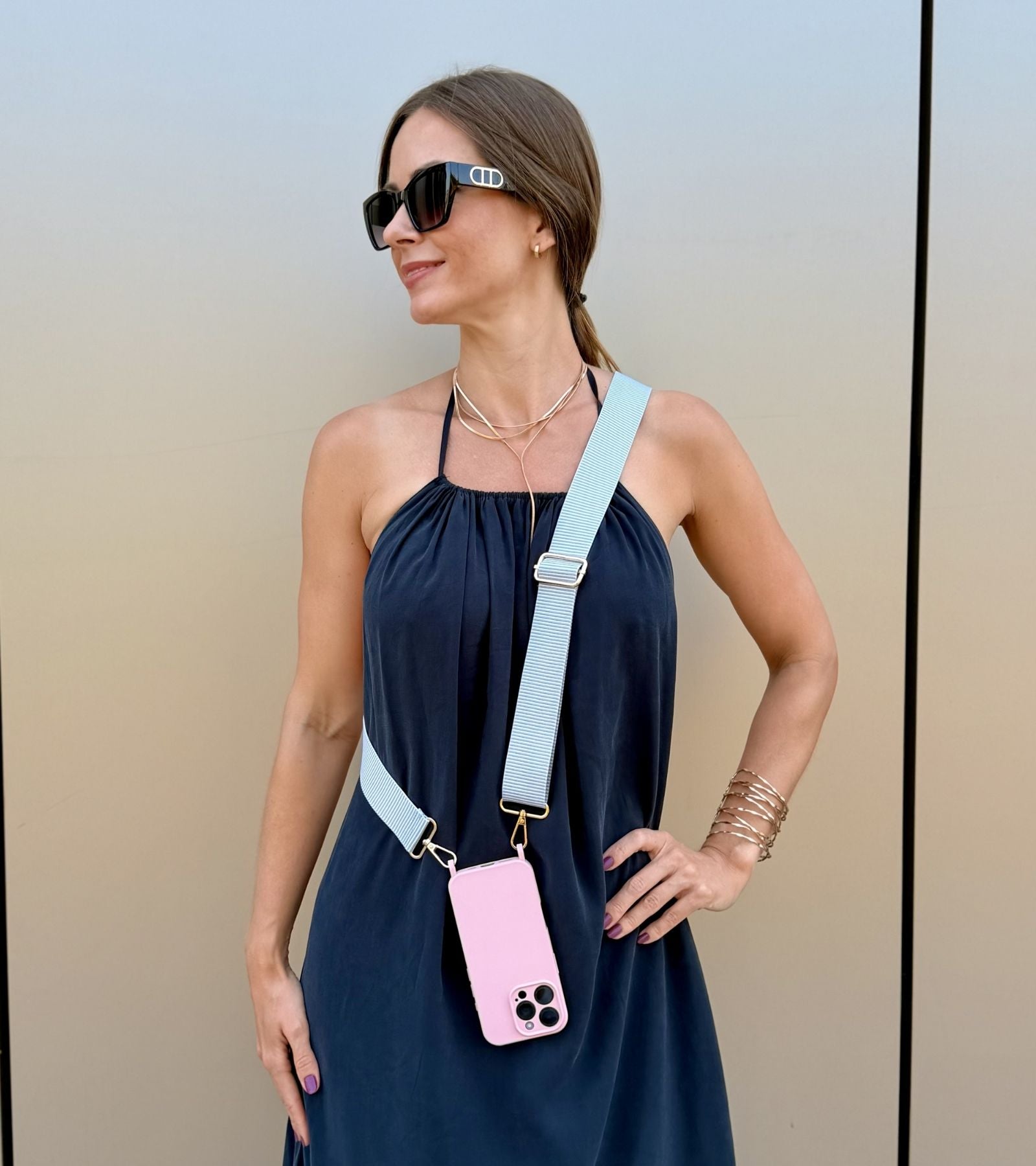 Strappy Set Line Soft Gray na modelke – crossbody popruh na mobil v sivej farebnej kombinácii a ružový kryt na iPhone ako súčasť outfitu.