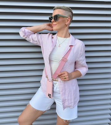 Strappy Set Line Soft Pink na modelke – crossbody popruh na mobil v ružovej farebnej kombinácii a ružový kryt na iPhone ako súčasť outfitu.