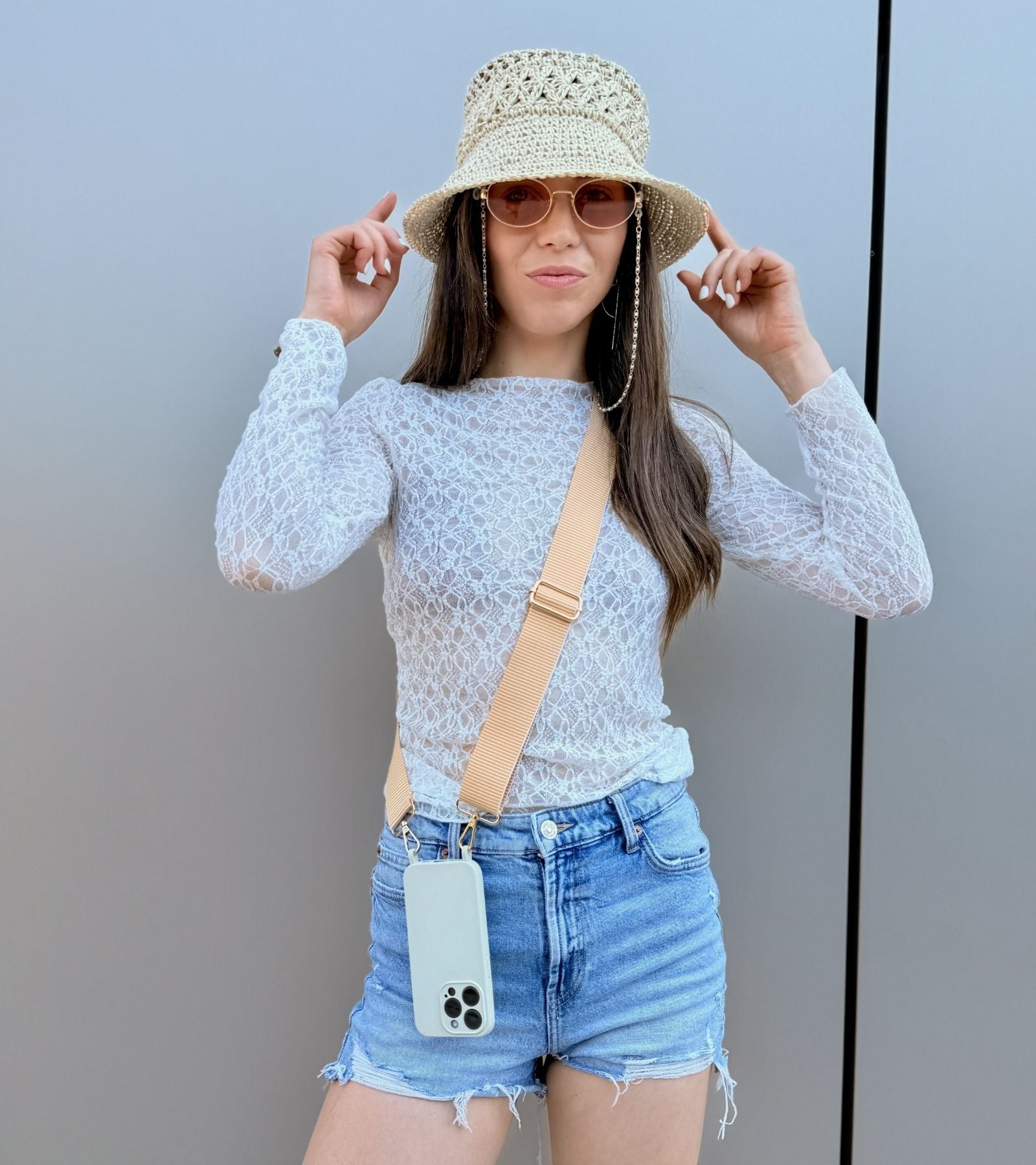 Strappy Set Line Sunny Yellow na modelke – crossbody popruh na mobil v žltej farebnej kombinácii a béžový kryt na iPhone ako súčasť outfitu.