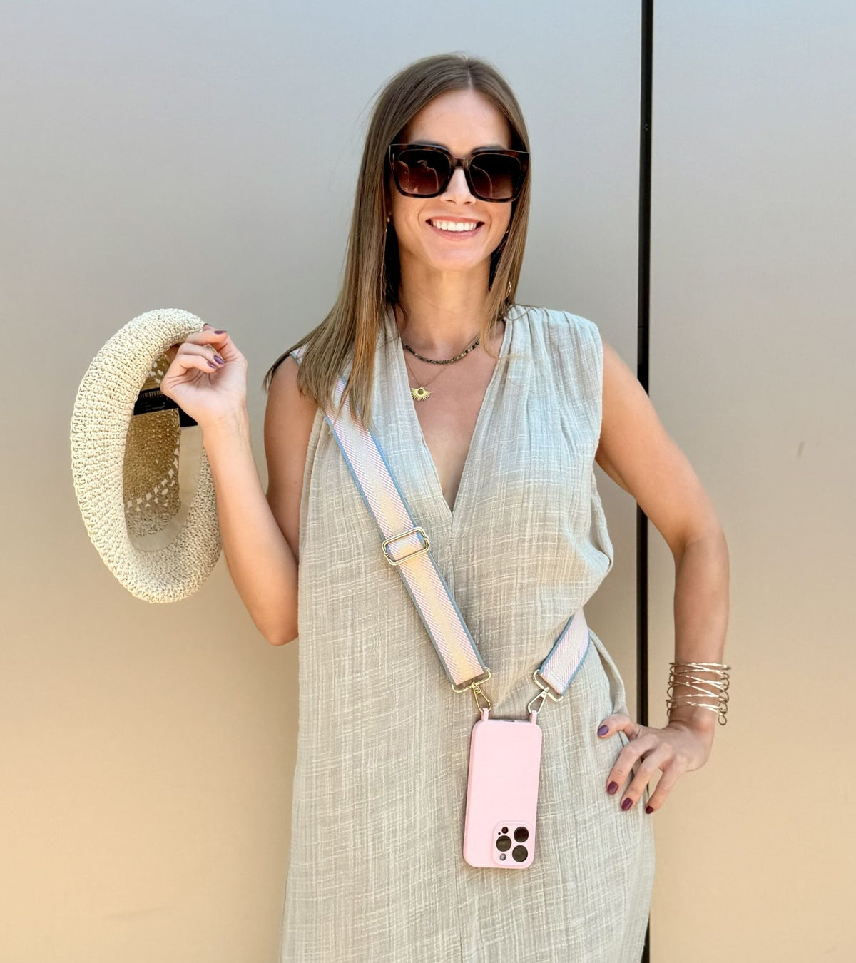 Strappy Set Retro Pastel Pink na modelke – retro pásikavý crossbody popruh na mobil v ružovej farebnej kombinácii a ružový kryt na iPhone ako štýlový módny doplnok.